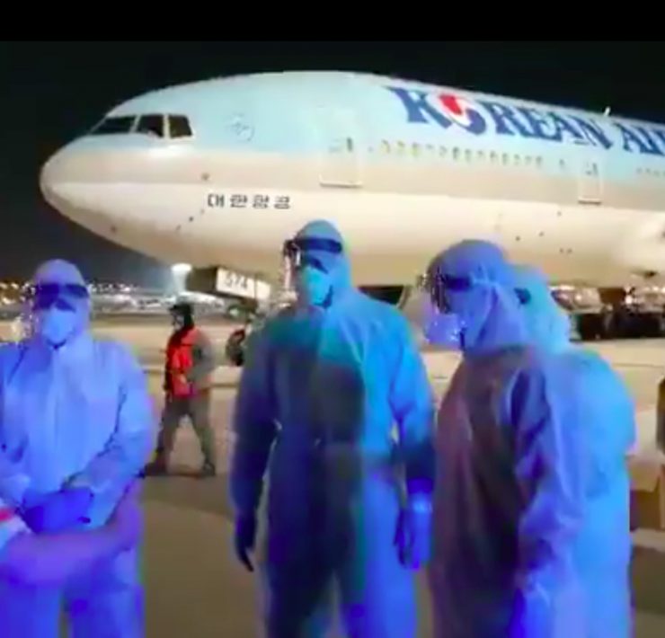 a group of people wearing protective gear and standing in front of a plane