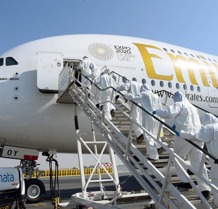 people in hazmat suits walking up a plane