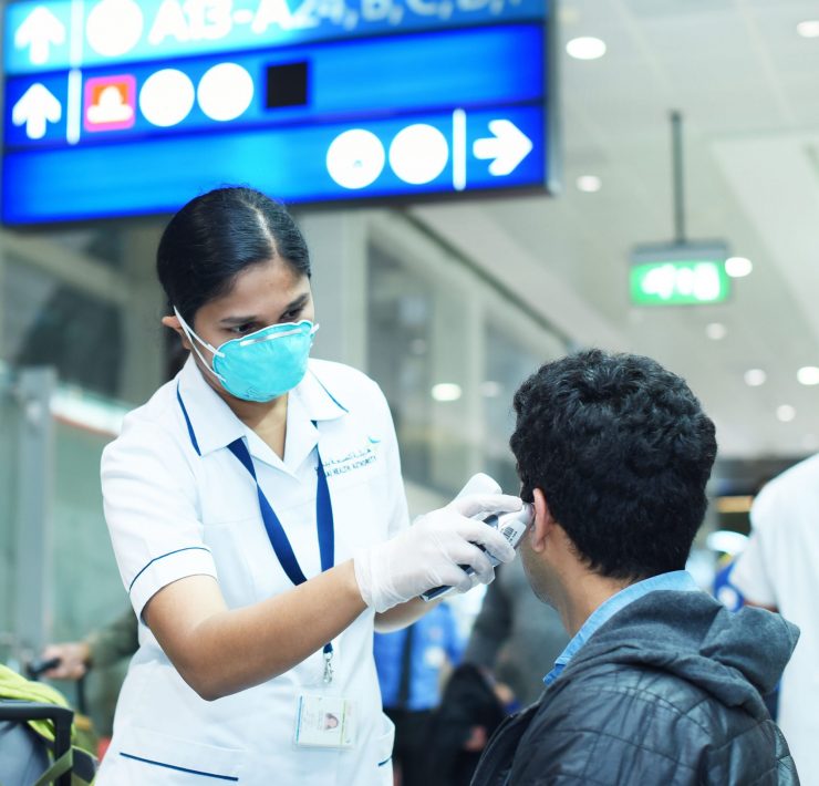 a person wearing a mask and gloves checking a man's ear