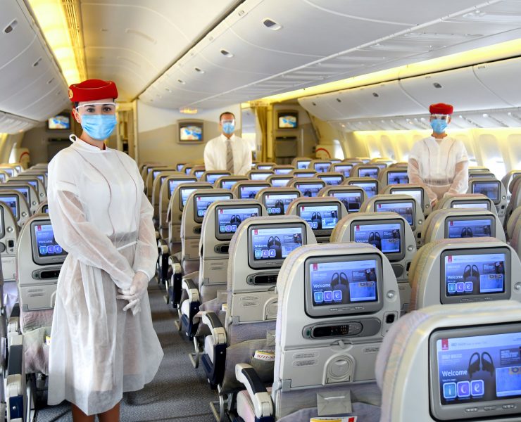 a group of people wearing face masks and standing in an airplane