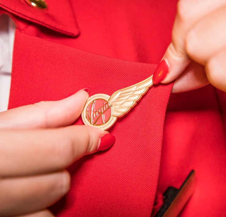 a person putting a gold pin on a red shirt