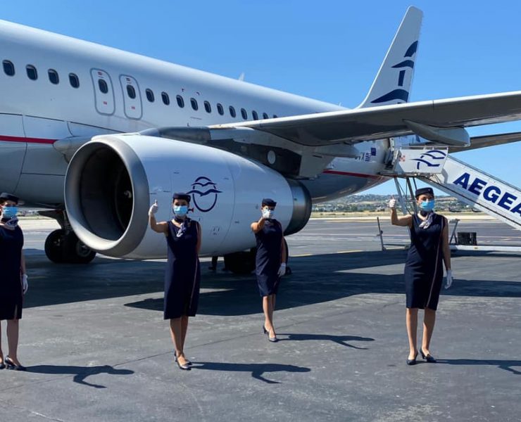 a group of women wearing face masks standing in front of an airplane