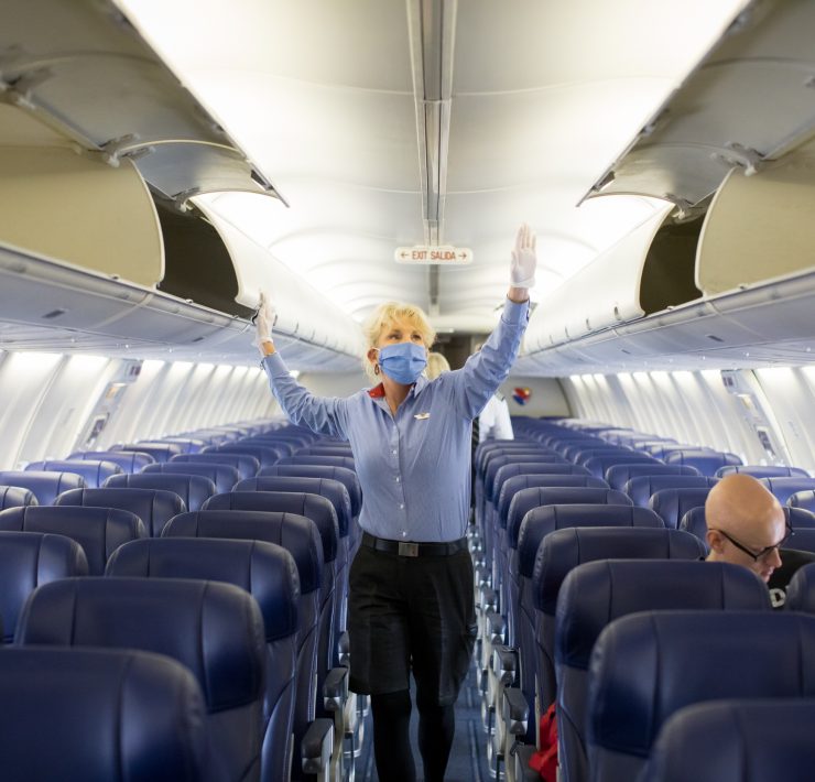 a woman wearing a mask and standing in an airplane