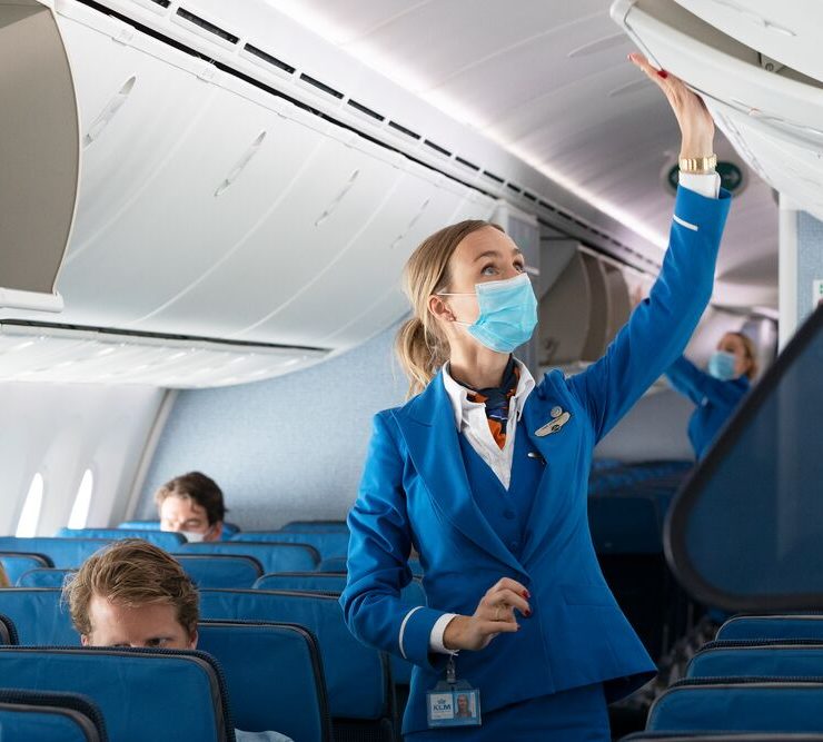 a woman wearing a mask and standing in an airplane