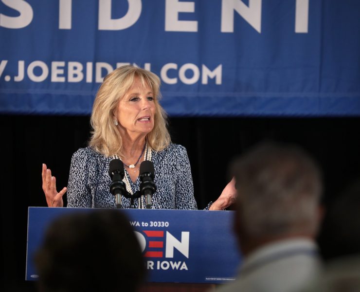 a woman standing at a podium with microphones