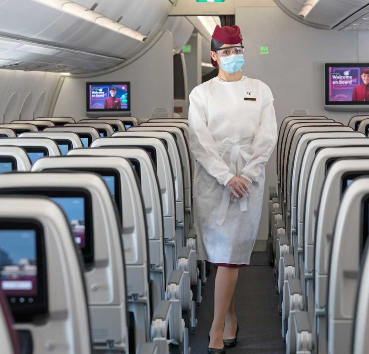 a woman wearing a mask and standing in a plane