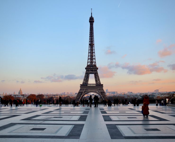 a large metal tower with people in front of it with Eiffel Tower in the background