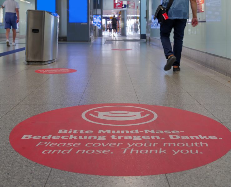 a person walking in a hallway with red circle signs on the floor