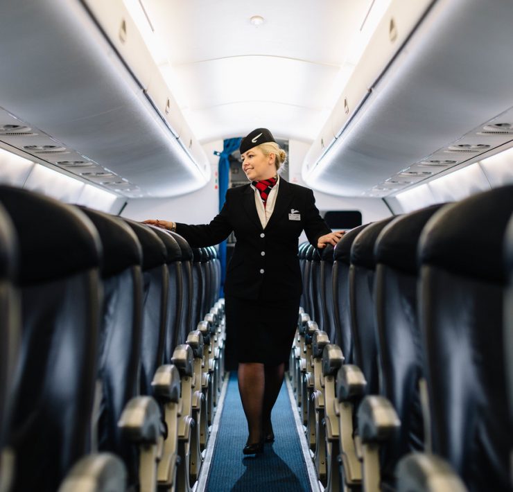a woman in a flight attendant uniform walking on an airplane