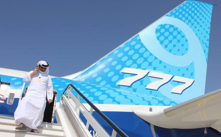 a man in a white suit walking up the stairs of an airplane