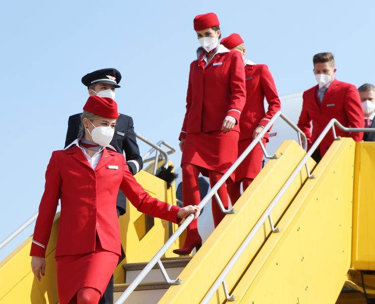 a group of people wearing red uniforms and masks walking up stairs