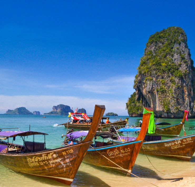 boats on the water by a large rock