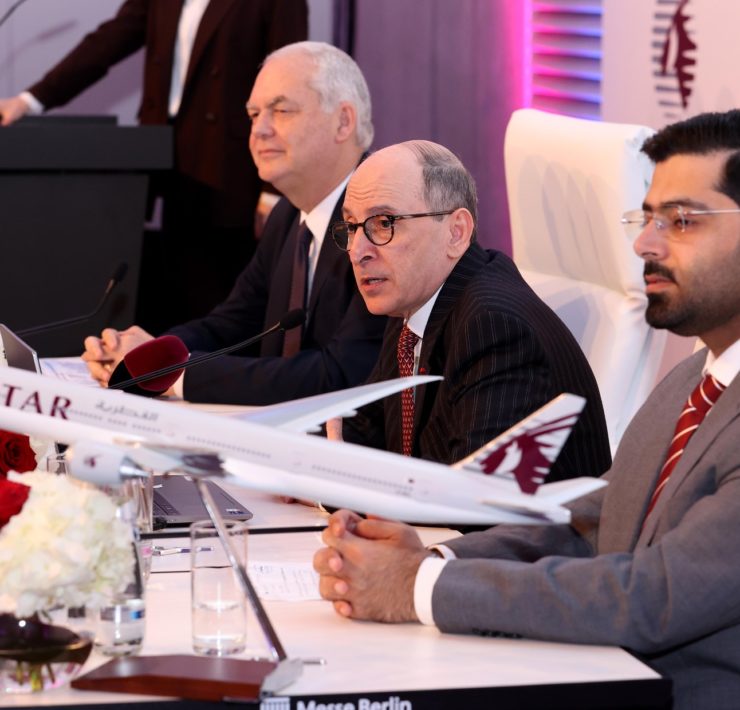 a group of men sitting at a table with a model airplane