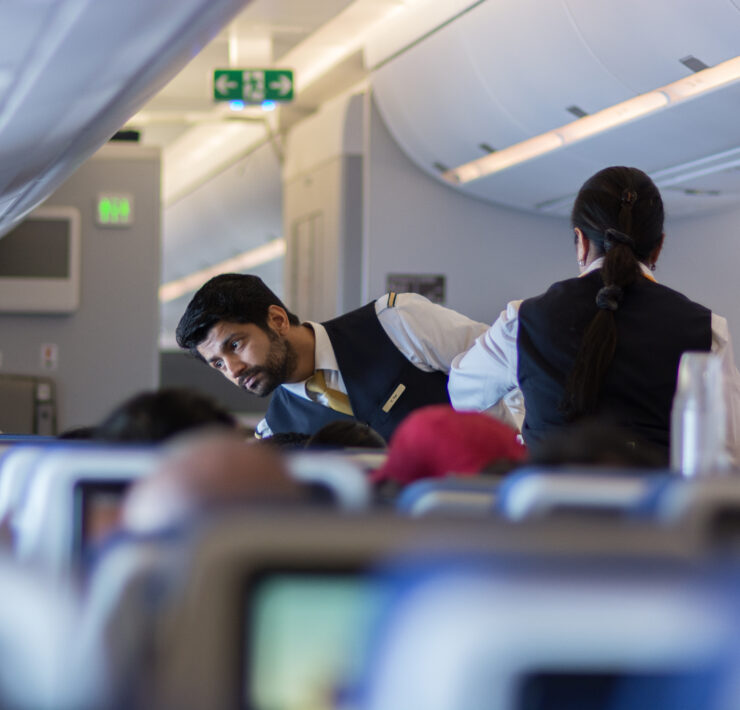 a man in a vest and vest standing next to a woman in an airplane