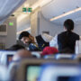 a man in a vest and vest standing next to a woman in an airplane