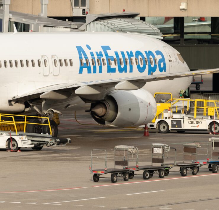 a large airplane with luggage carts and a building