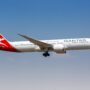 a white airplane with red and white markings flying in the sky