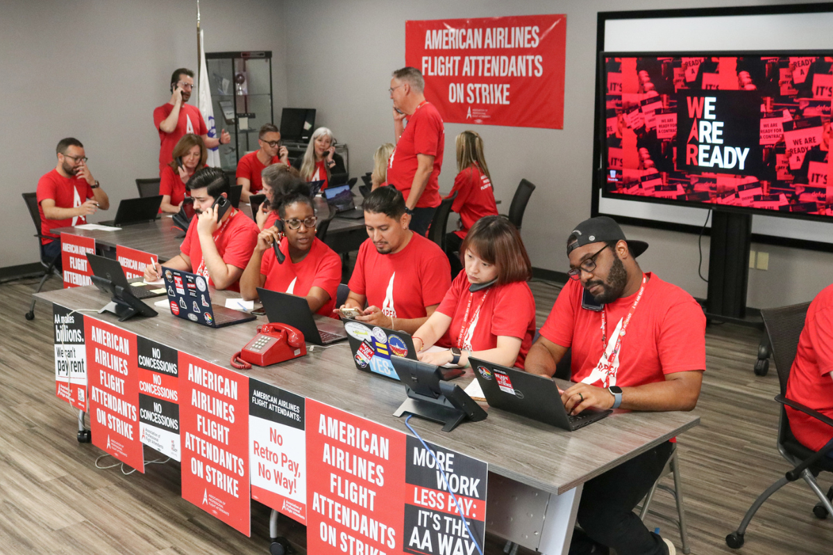 a group of people in red shirts sitting at a long table with laptops