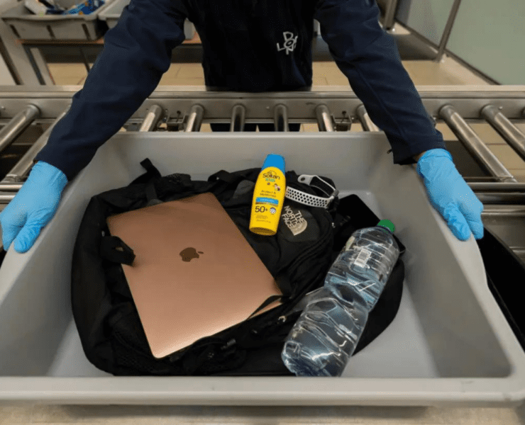 a person holding a tray with a laptop and a bottle of sunblock