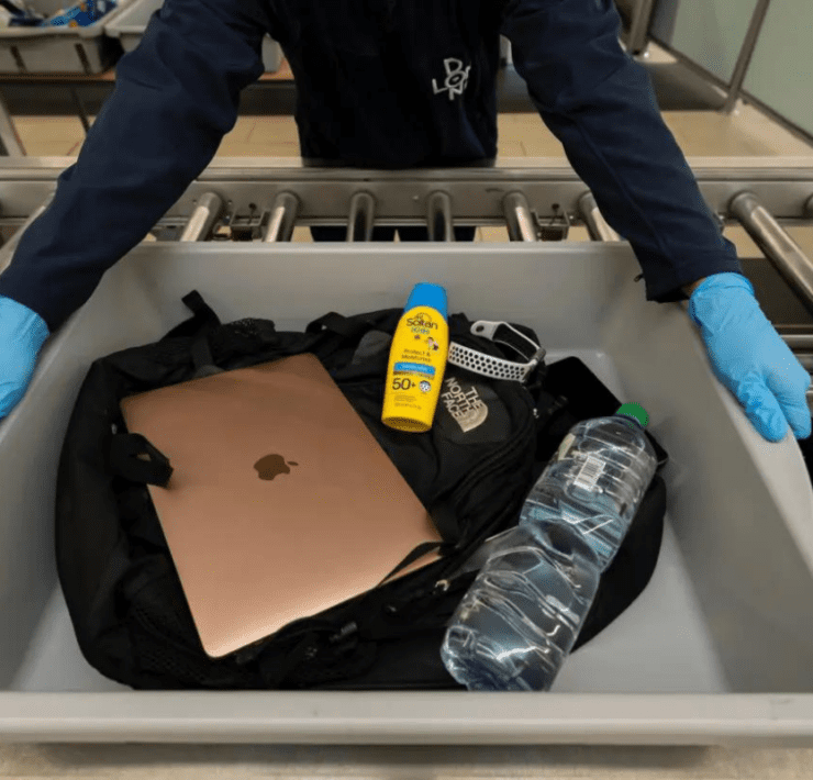 a person holding a tray with a laptop and a bottle of sunblock