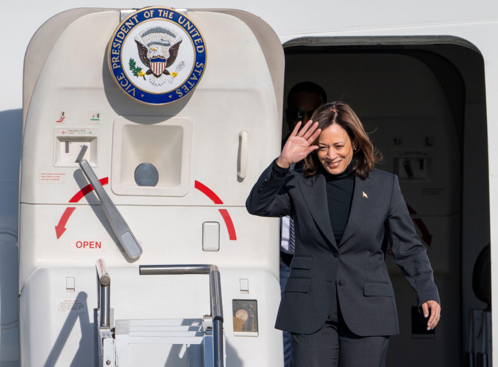 a woman in a suit waving in front of a plane