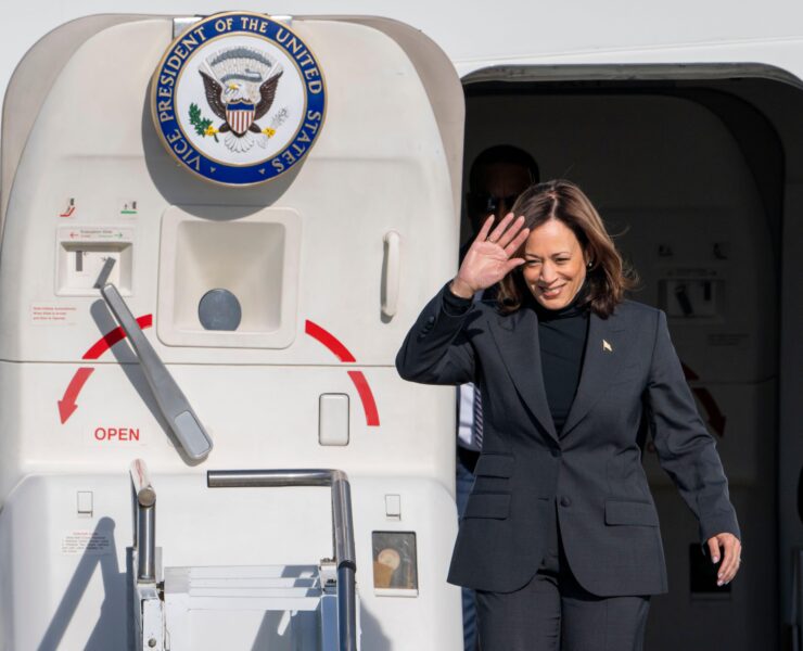 a woman in a suit waving in front of a plane