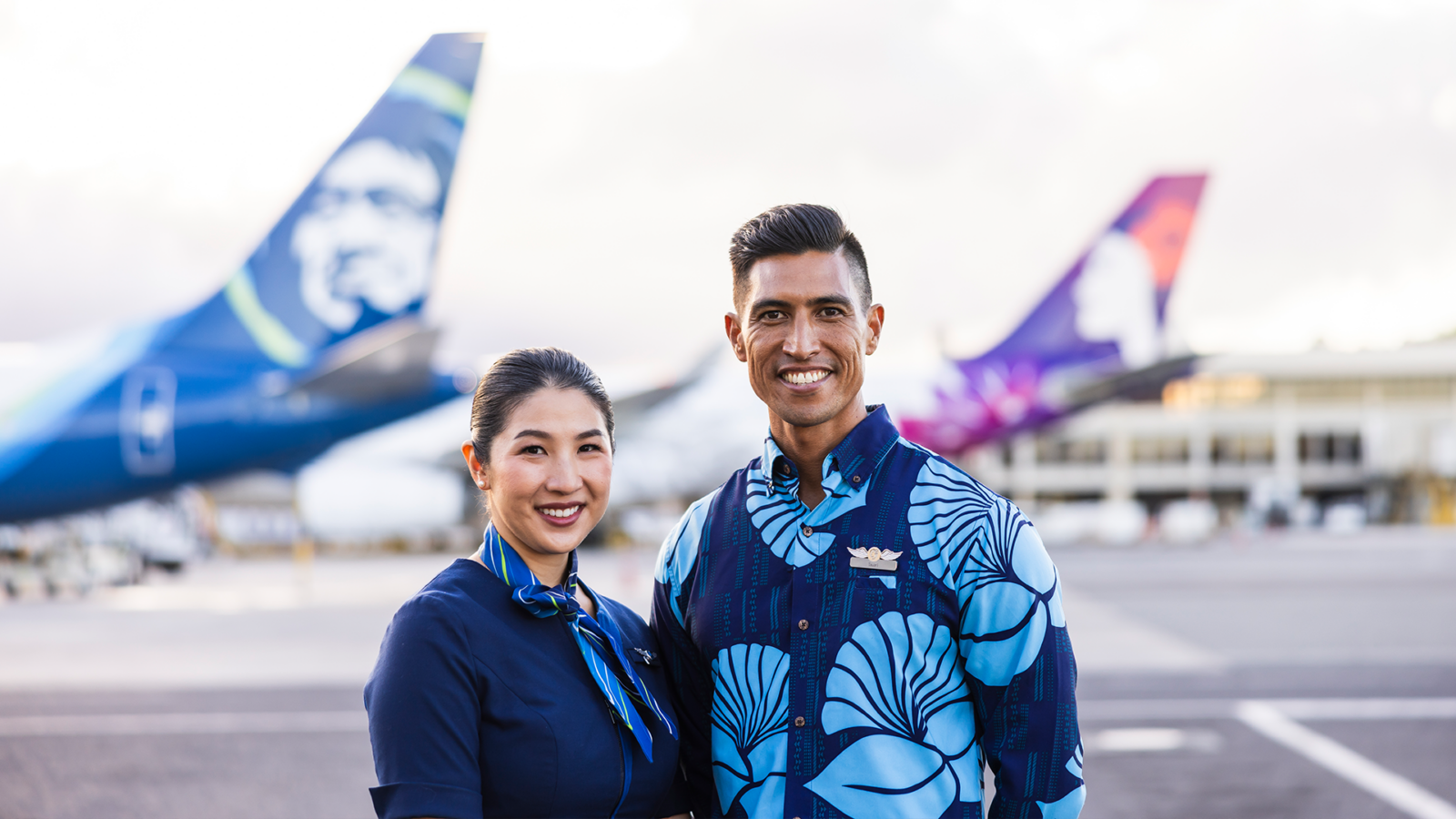 a man and woman standing in front of airplanes