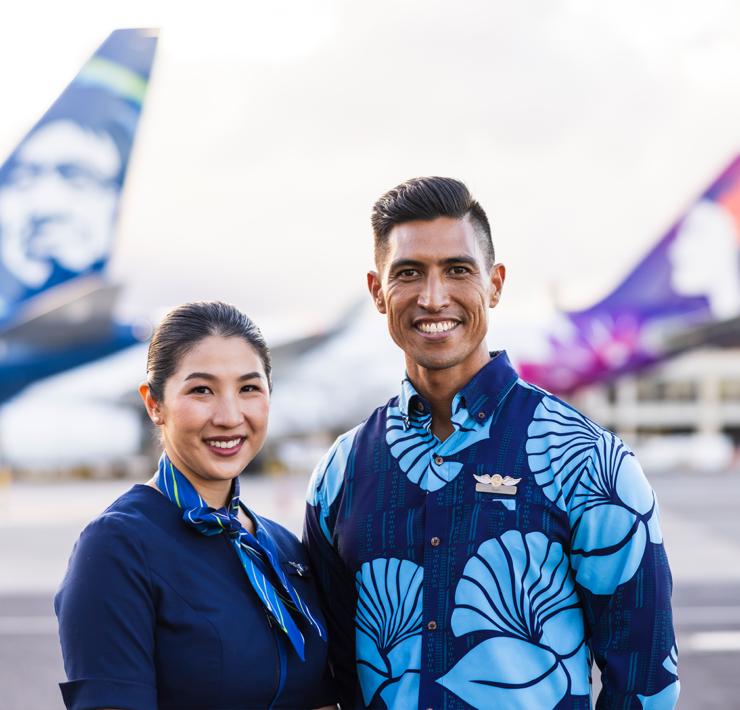 a man and woman standing in front of airplanes