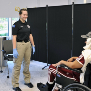 a woman standing next to a person in a wheelchair