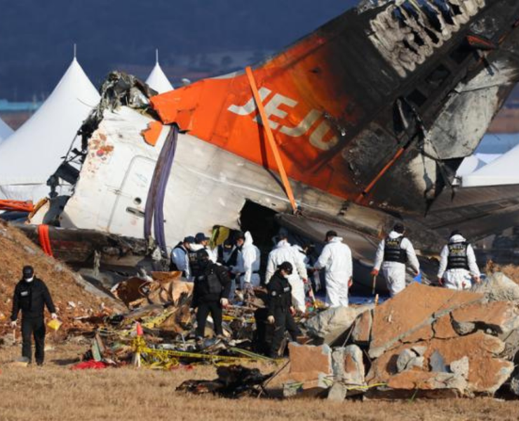 a group of people in white uniforms near a crashed plane