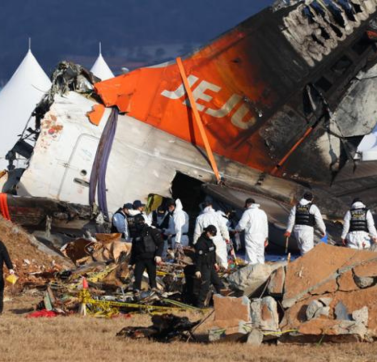 a group of people in white uniforms near a crashed plane