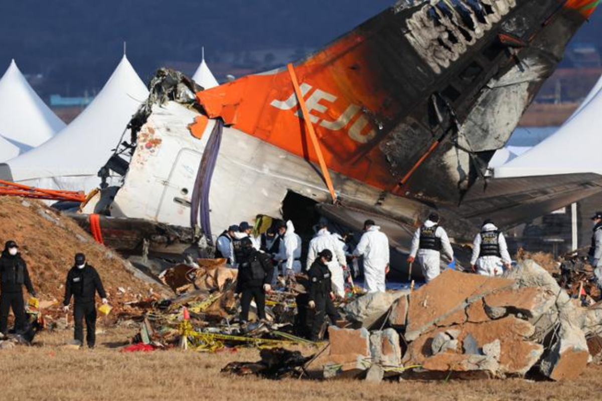 a group of people in white uniforms near a crashed plane