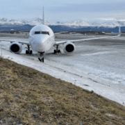 a plane on a runway with snow and mountains in the background