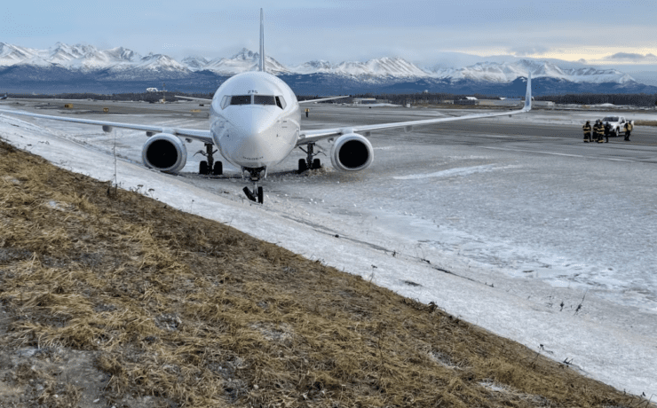 a plane on a runway with snow and mountains in the background