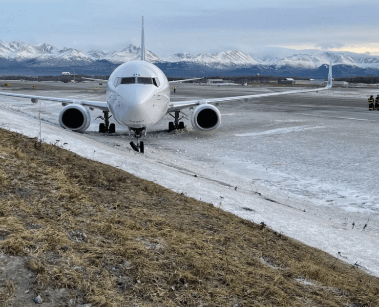 a plane on a runway with snow and mountains in the background