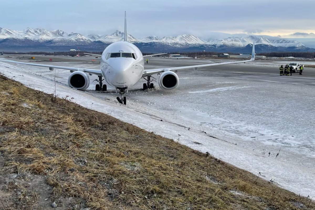 a plane on a runway with snow and mountains in the background