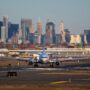 a plane on a runway with a city in the background